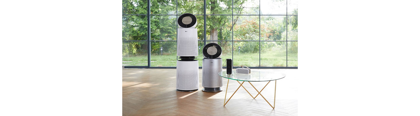 The four LG Purifier models ranging from the residential to handy portable model displayed in an open room with a large window overlooking the garden.