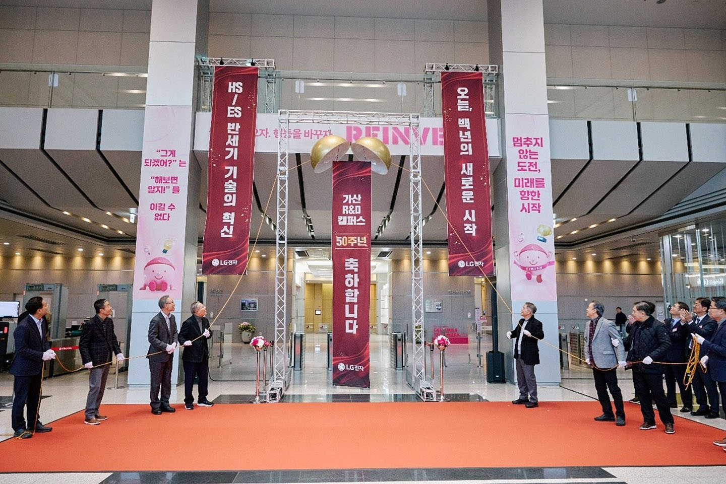 Attendees gather on a red carpet at the 50th anniversary ceremony of the Gasan R&D Campus, looking at vertical banners with the message “50 Years of Technology and Passion, a Promise for Tomorrow.”