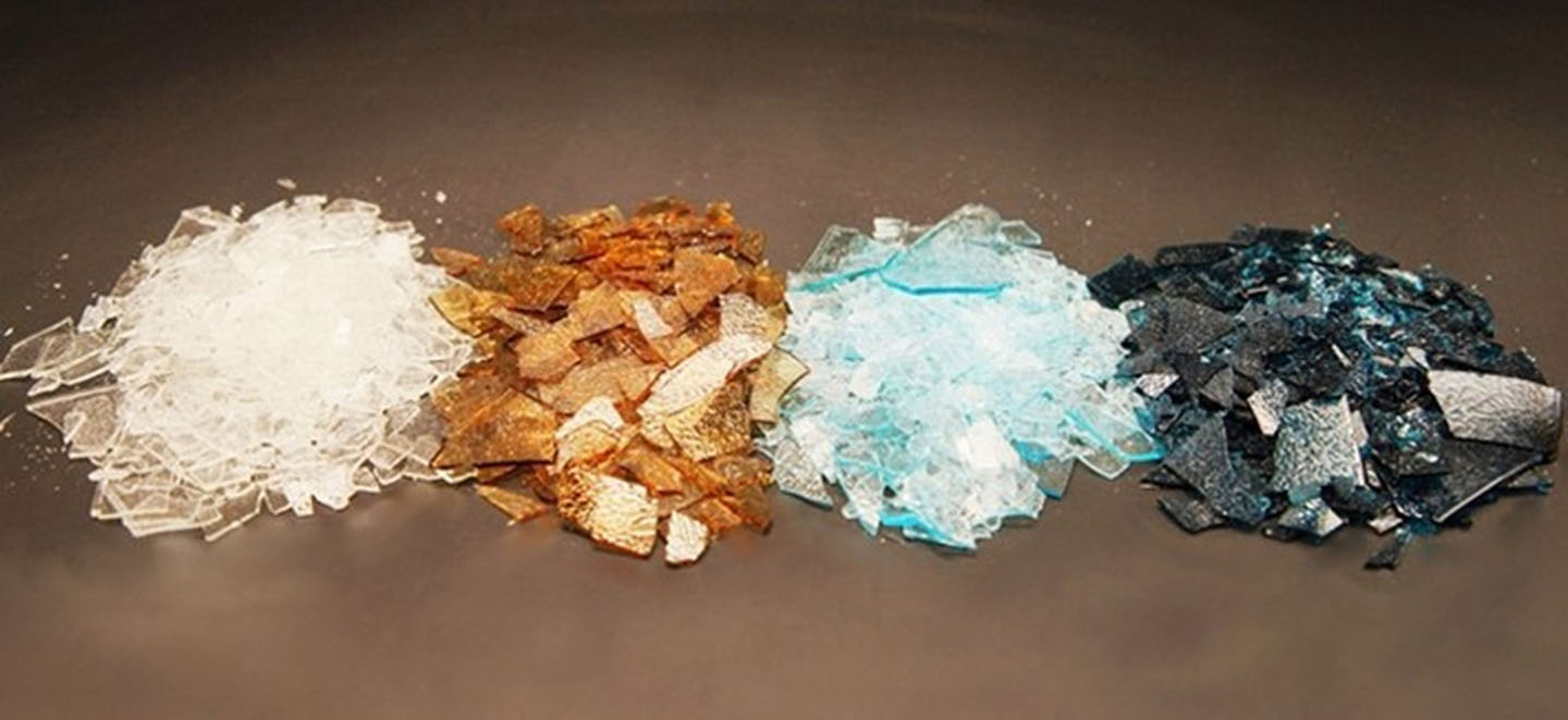 Various material flakes in different colors are arranged in separate piles against a dark background.