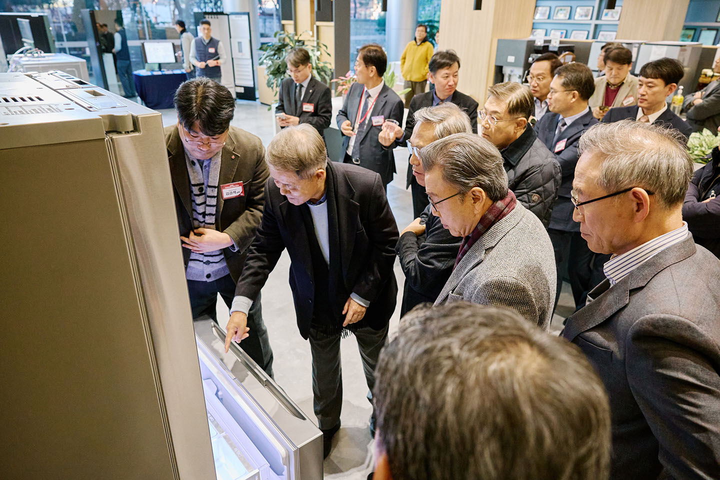 Visitors gather around an LG refrigerator while a presenter demonstrates the product during an exhibition event.
