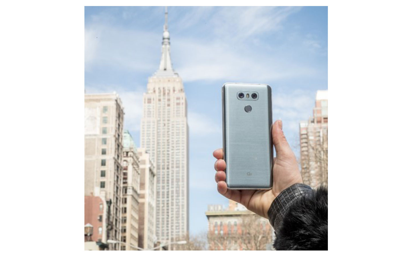 A person holds up the LG G6 to show its rear side with the Empire State Building in the background