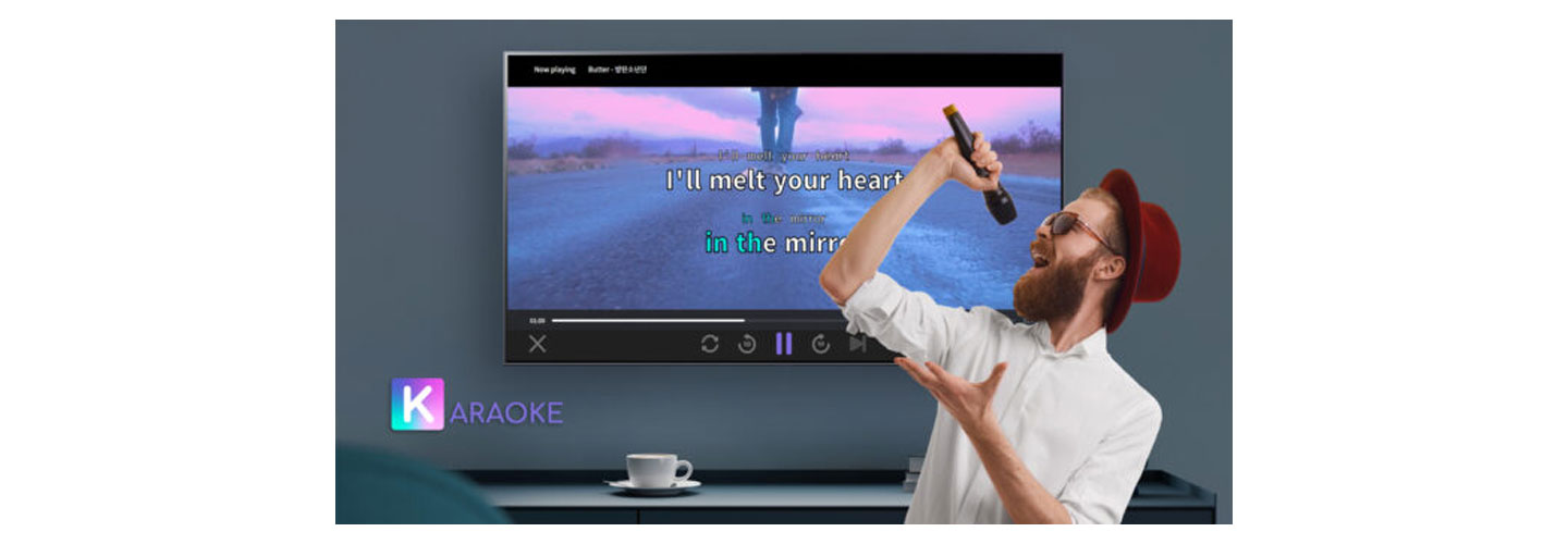 A man singing enthusiastically into a microphone using the K-araoke service on his LG Smart TV.