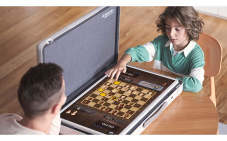 A father and son play a game of chess game at a desk using the LG StanbyME Go model in table mode.