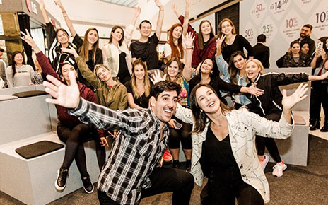 Social media celebrities take a group photo with their hands raised high.