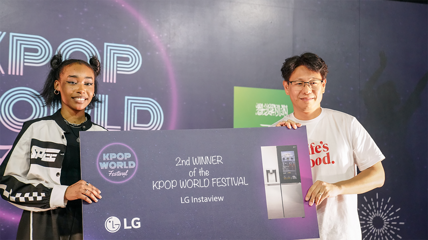 A picture of the 2nd winner posing on stage with an LG employee