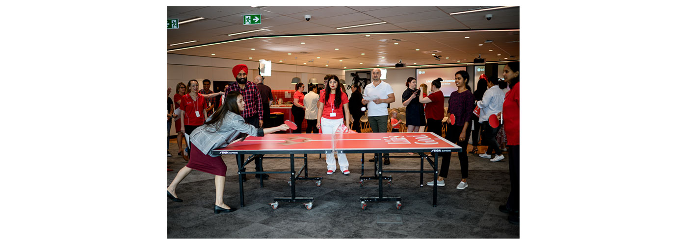 An image of people playing ping poing gathered around