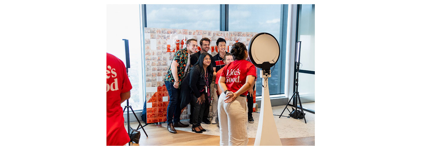 An image of people taking a picture together in front of a LG logo photo wall