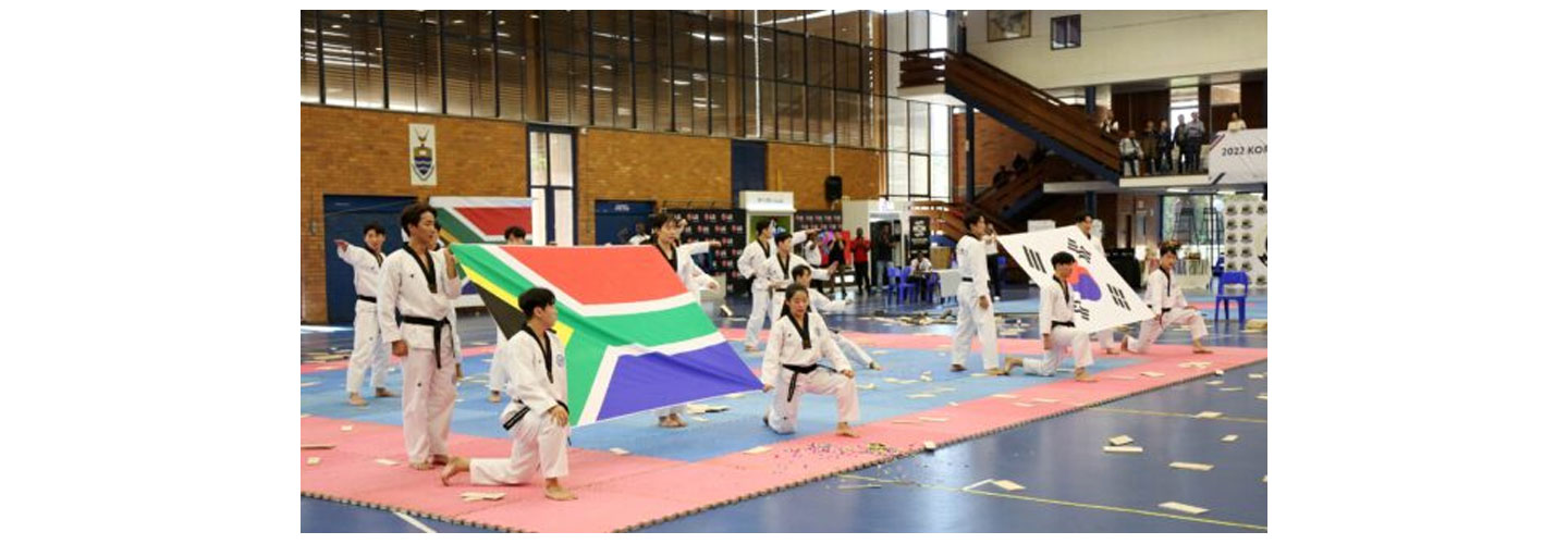 Taekwondo athletes holding the national flags of South Africa and Korea at the end of their performance