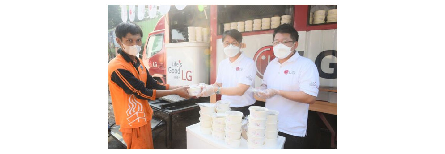 Lee Taijin, President of LG Electronics Indonesia, and Kris Lee, Product Marketing Director of Home Appliances LG Electronics Indonesia, serve food to a waste disposal worker in Jakarta
