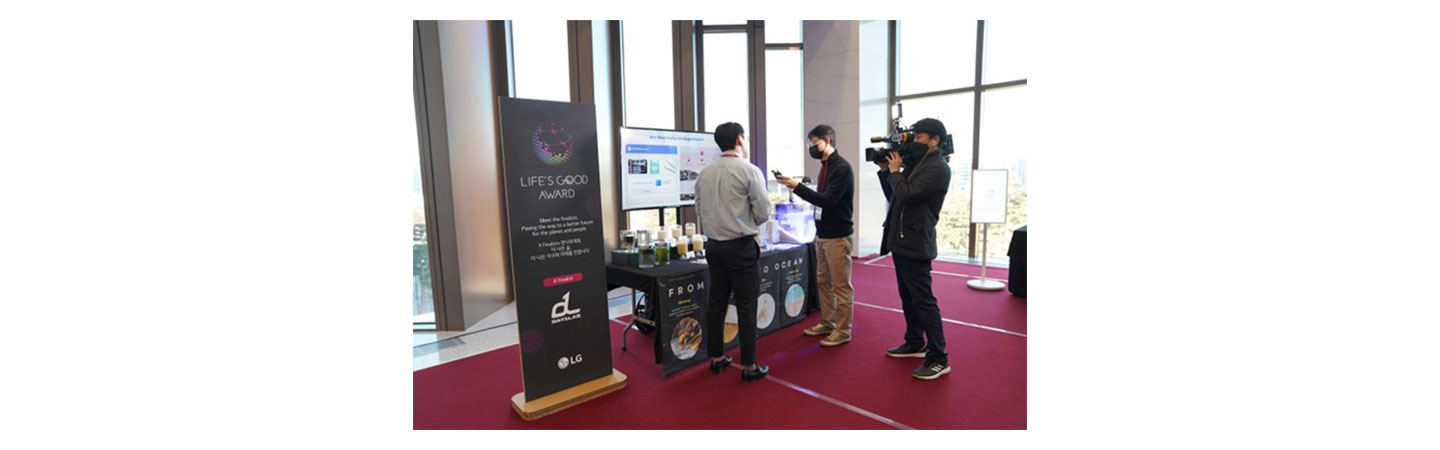 Day1Lab’s booth at the LIFE’S GOOD AWARD Conference, with a representative discussing the solution with a camera crew.