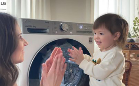 A promotional image of the Care for What You Wear campaign with a mother playing with her child in front of LG washer. 