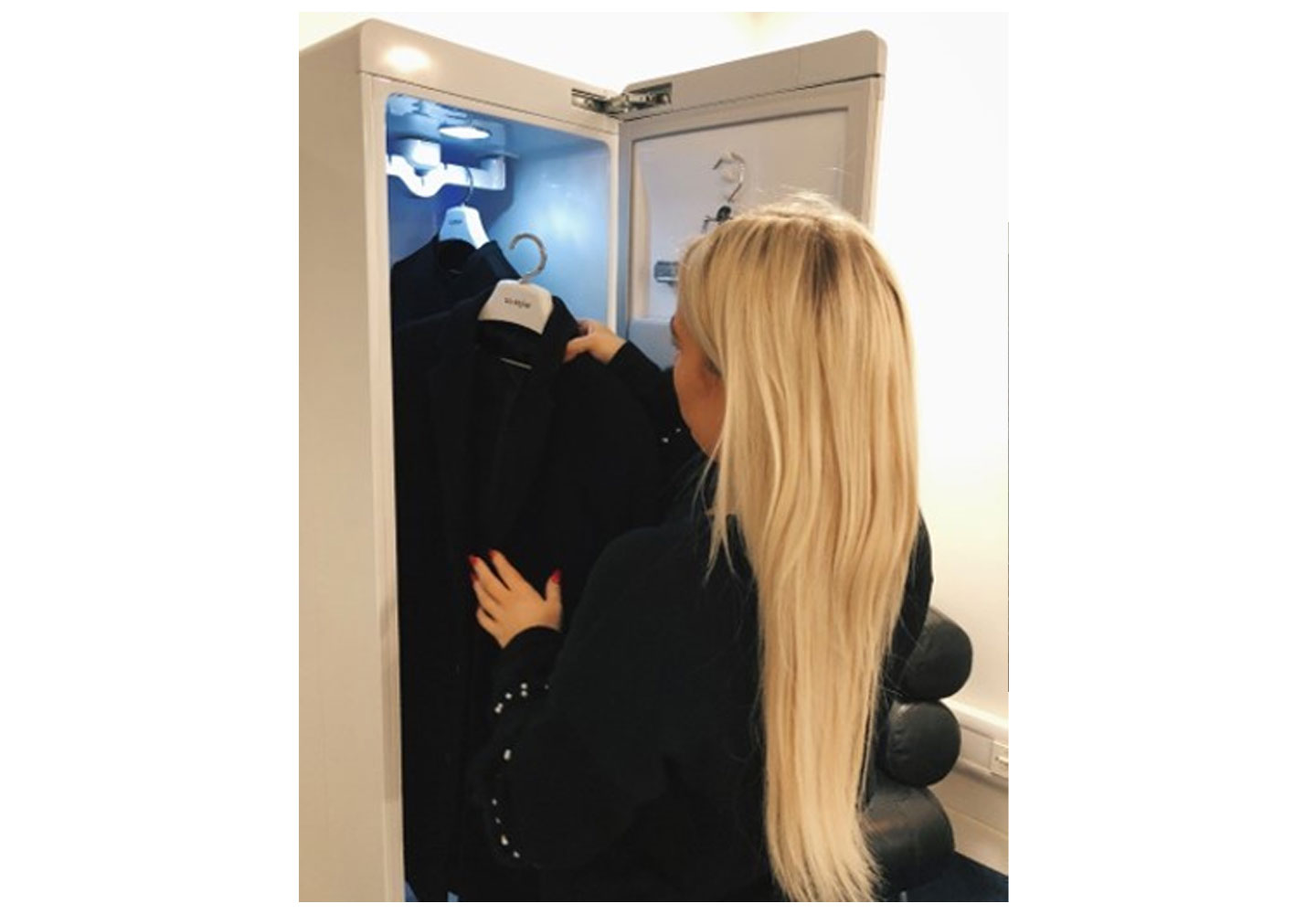 A woman puts her black smart coat inside the LG Styler at the event