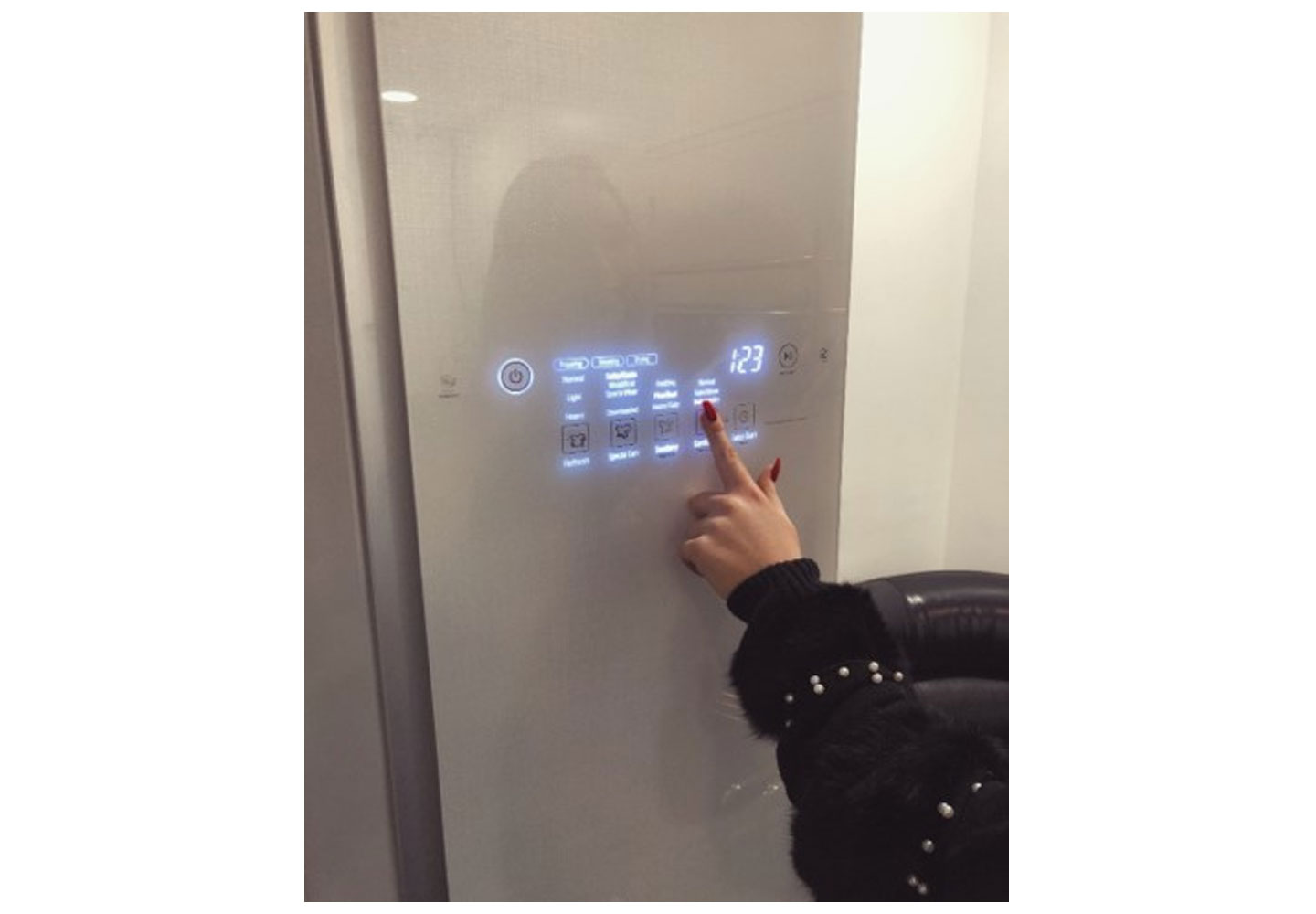 A woman pushes a button on the front door display panel of the LG Styler to set it to cleaning mode