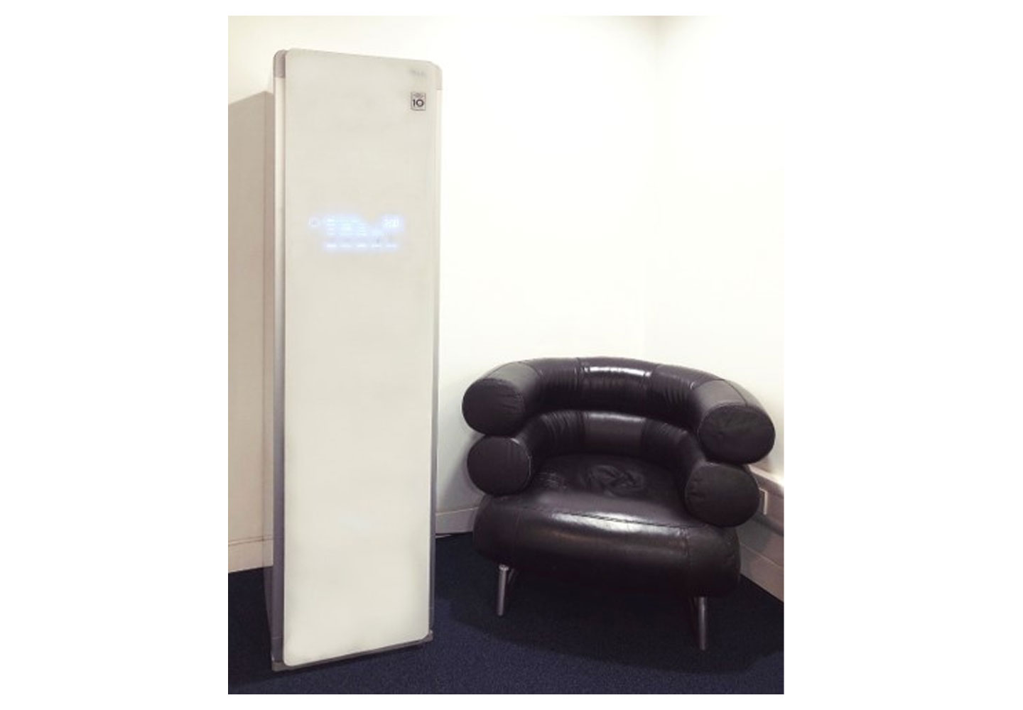 The LG Styler is positioned next to a luxury leather-upholstered chair at the UK launch event