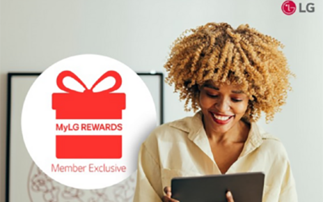 A photo of a woman smiling while looking at MyLg Rewards with a tab 