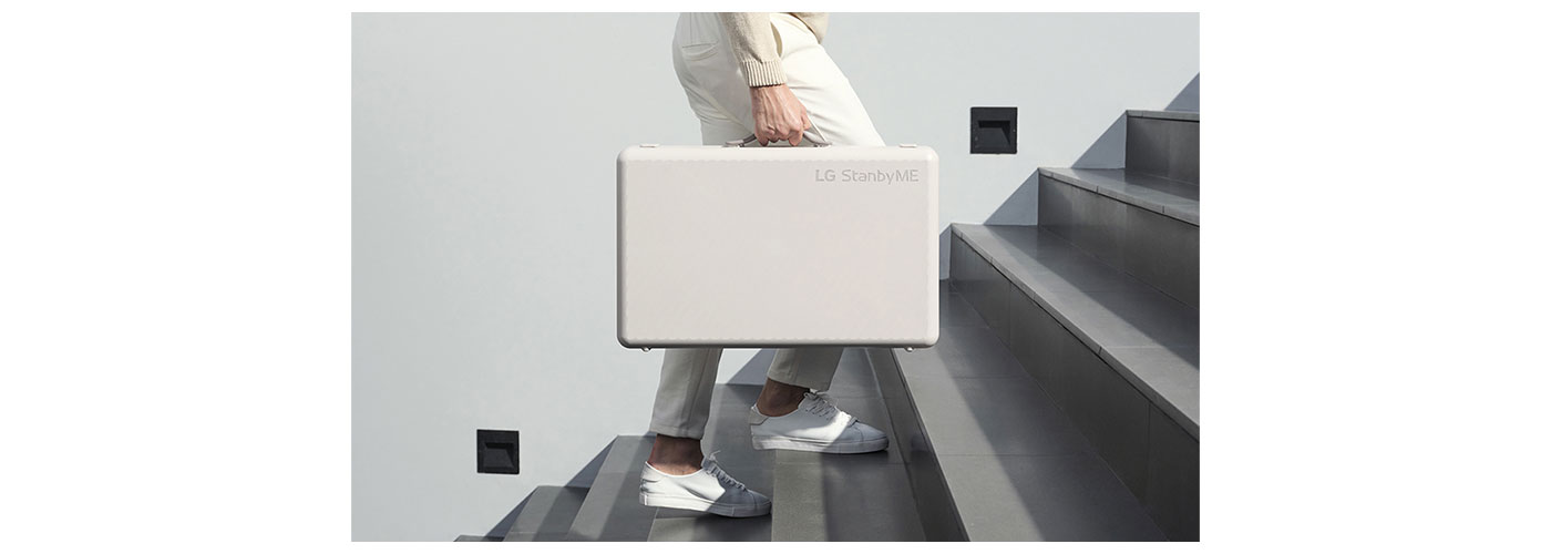 A photo of a person walking up the stairs while holding the folded LG StandbyME Go case