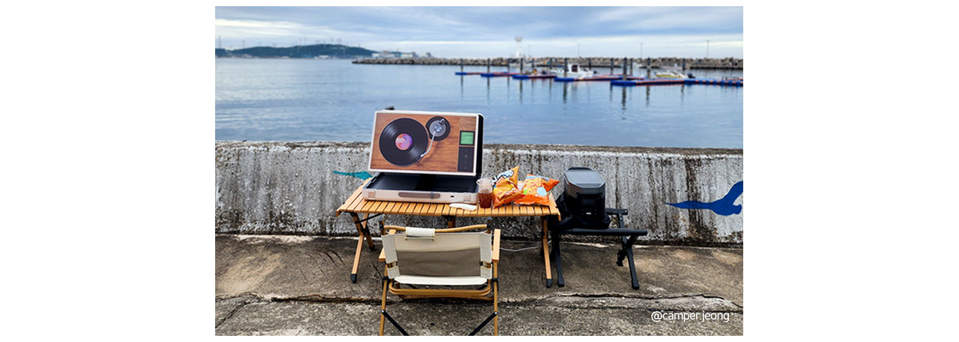 A photo of the LG StanbyME Go placed on a desk outside near the ocean