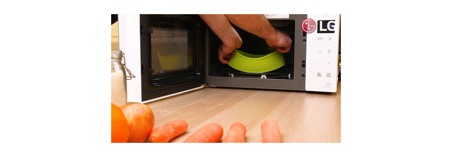 Chef Marques putting food in a green microwavable dish into LG NeoChef