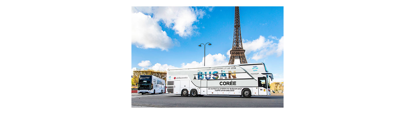 A photo of a big LG bus with the words 'A Busan Coree' passing by the Eiffel Tower