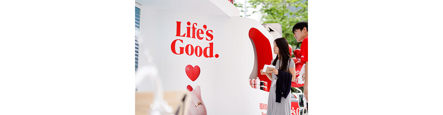 LG employees looking at the Life's Good image printed on the outside of the event truck