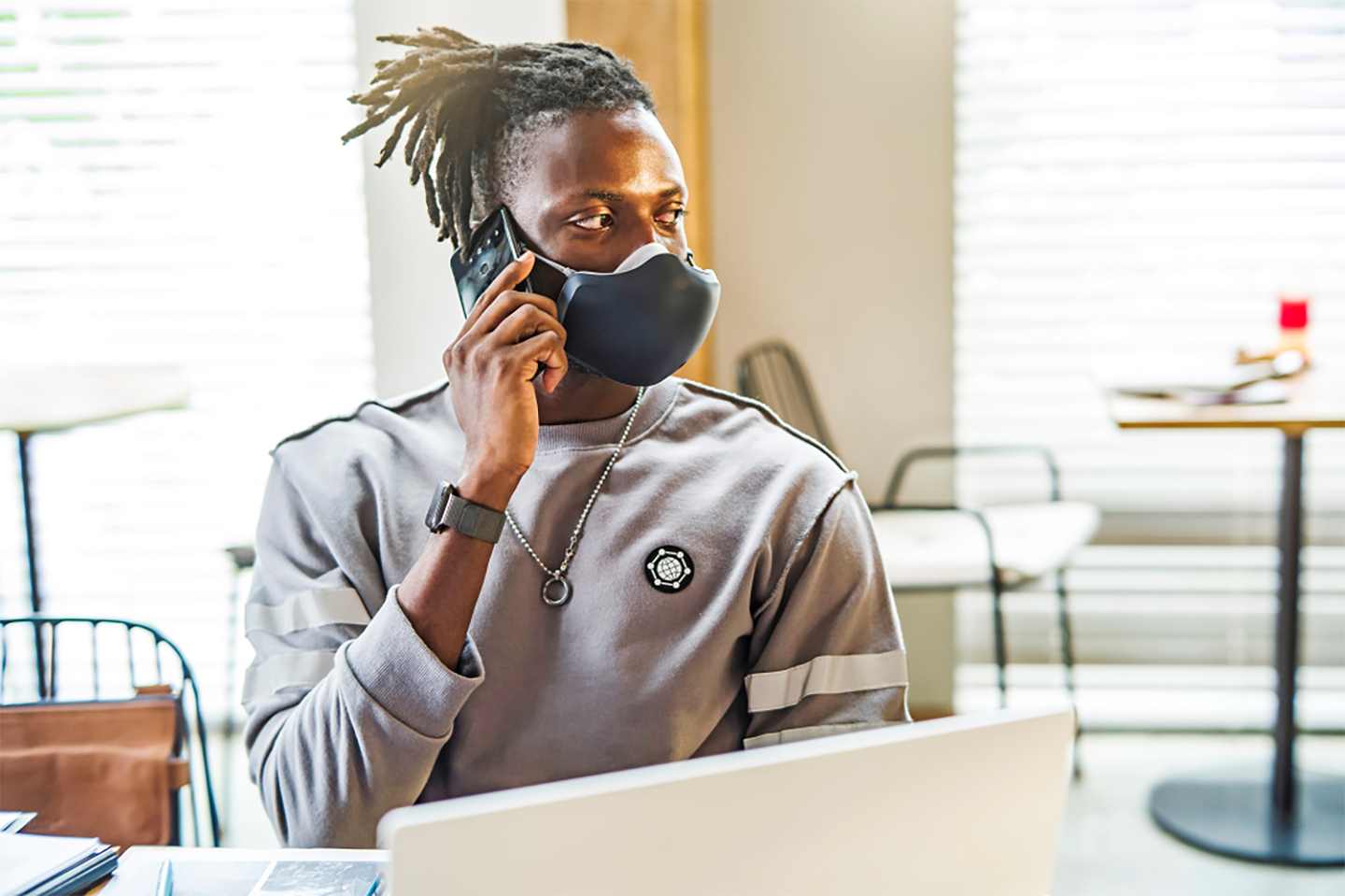 A man using his smartphone without removing LG PuriCare Wearable thanks to the clearness of VoiceOn technology.