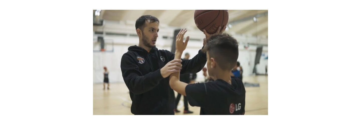 A basketball expert coaching an attendee on how to improve his game during the LG Athletes of Tomorrow program