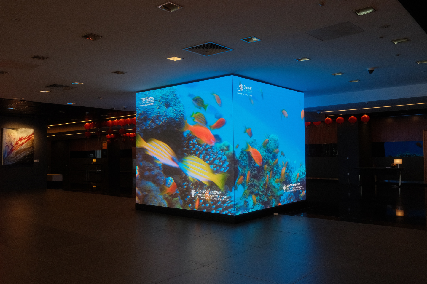 An LG LED display at Suntec Singapore showcases vivid underwater visuals, illuminating the dark venue interior.
