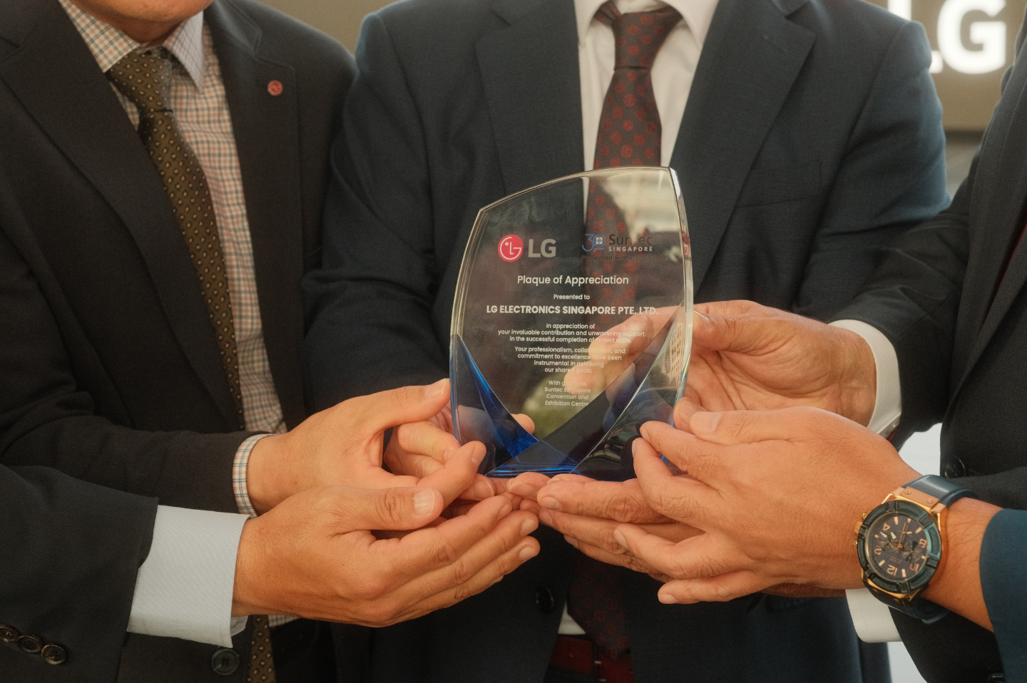 Several LG Electronics representatives are holding a plaque of appreciation from Suntec Singapore.