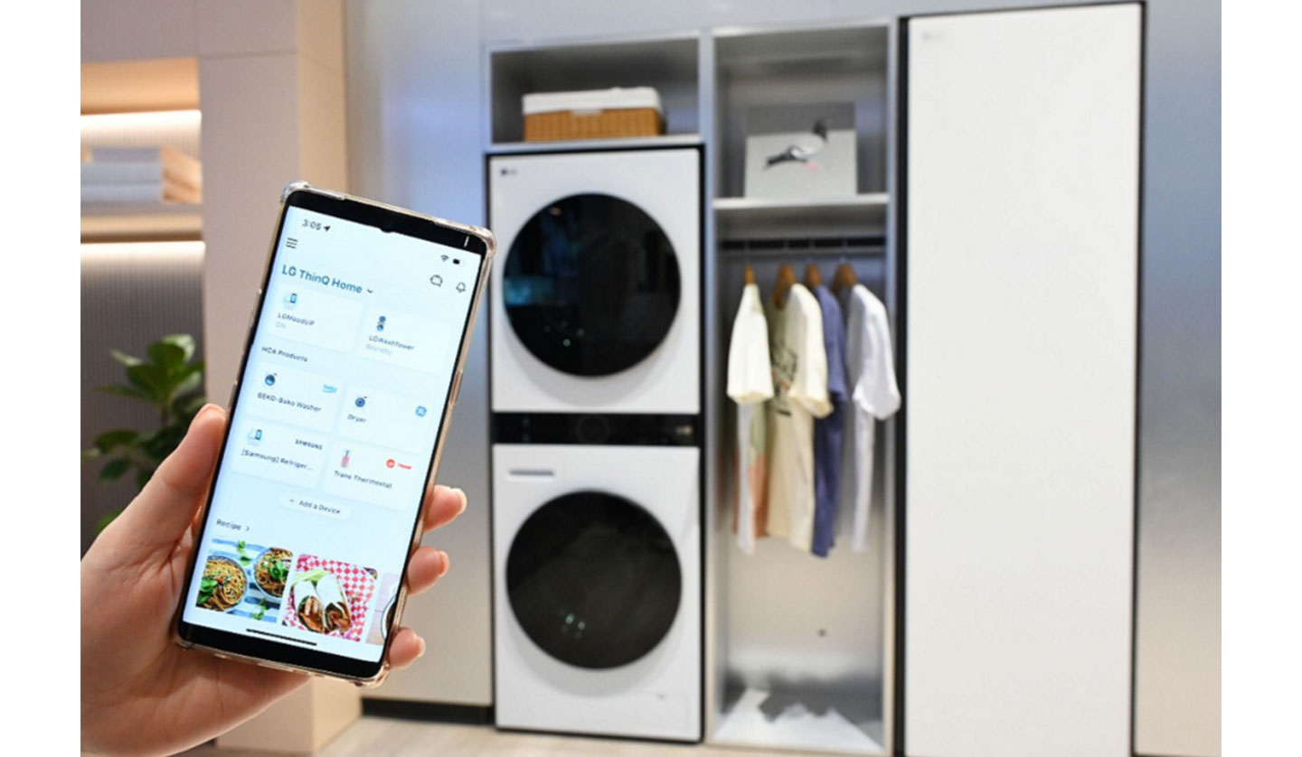 A human hand using LG ThinQ app to control the LG appliances in the back