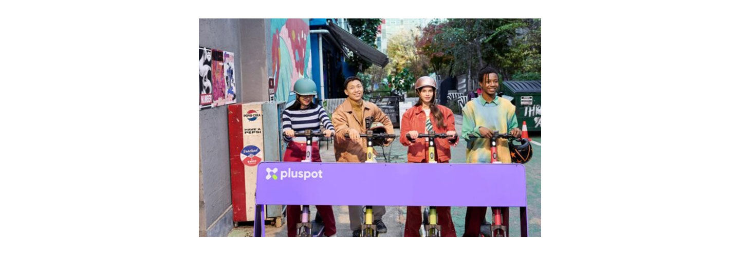 Four people using pluspot's scooters parked at the charging station