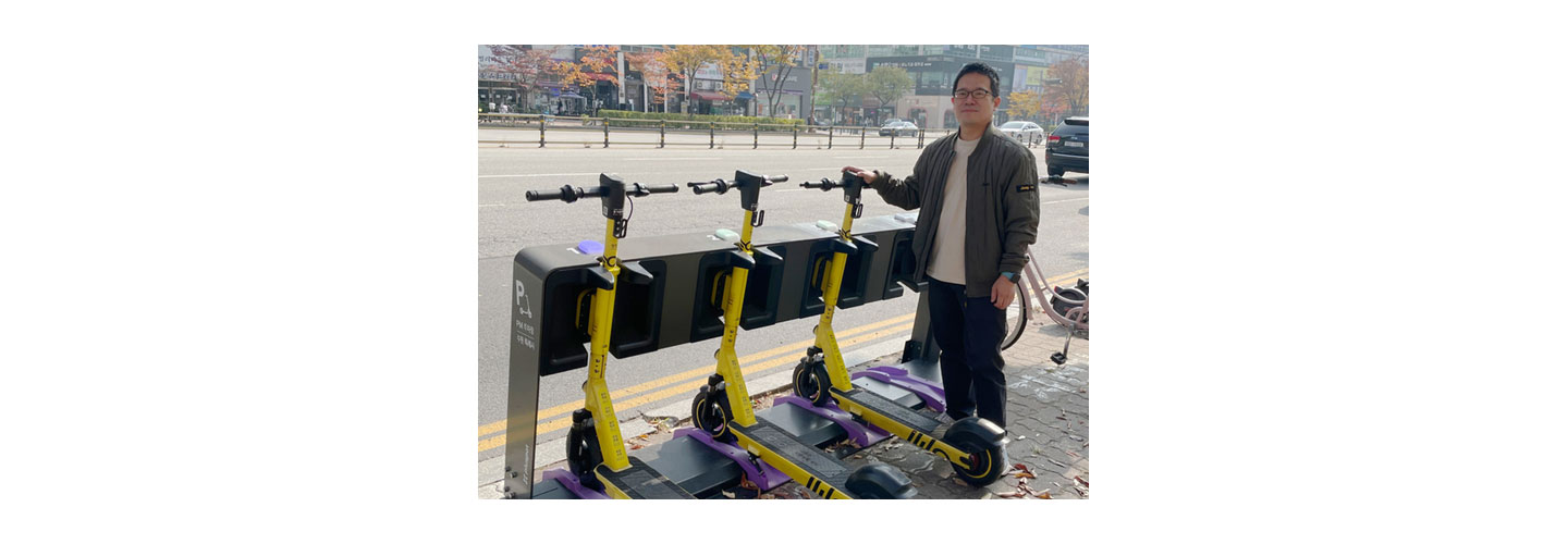 Do Won-dong, CIC head of LG’s CurrentDot company, posing with pluspot's scooters being charged at the station