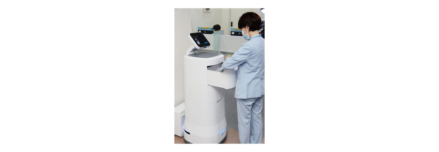 A medical worker taking equipment from one of LG CLOi ServeBot's useful drawers