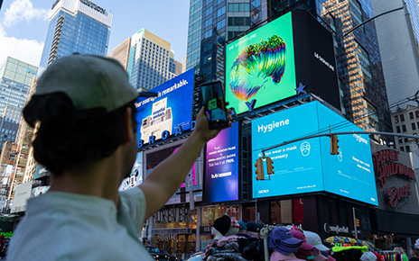 A man taking a picture of LG's massive, high-definition digital billboard in Time Square, New York displaying the artwork of David McLeod