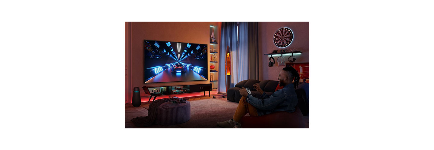 A man playing a racing game on LG OLED TV in his game-themed living room