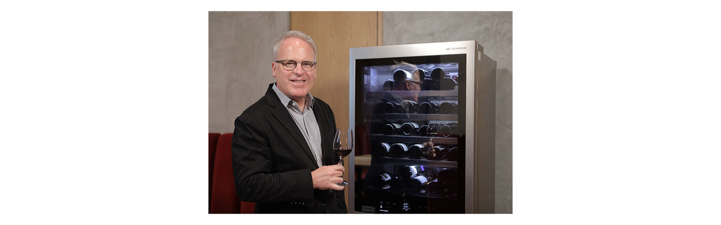 Famous wine critic James Suckling samples a glass of wine next to the new LG SIGNATURE Wine Cellar