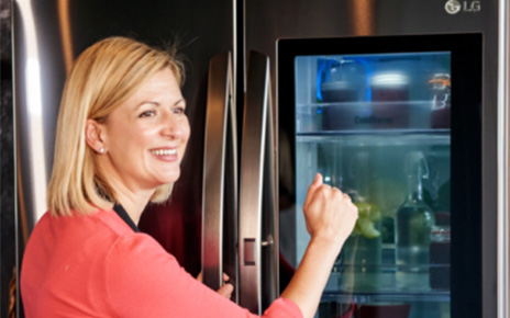 A lady in red shirts knocks on the transparent display panel of the LG InstaView Door-in-Door® refrigerator.