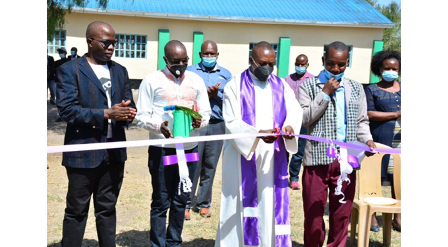 Father Joseph Mutuku cutting the ceremonial ribbon at the launch event of the project involving the construction of multiple facilities at Kyumbi Primary School in Machakos County.