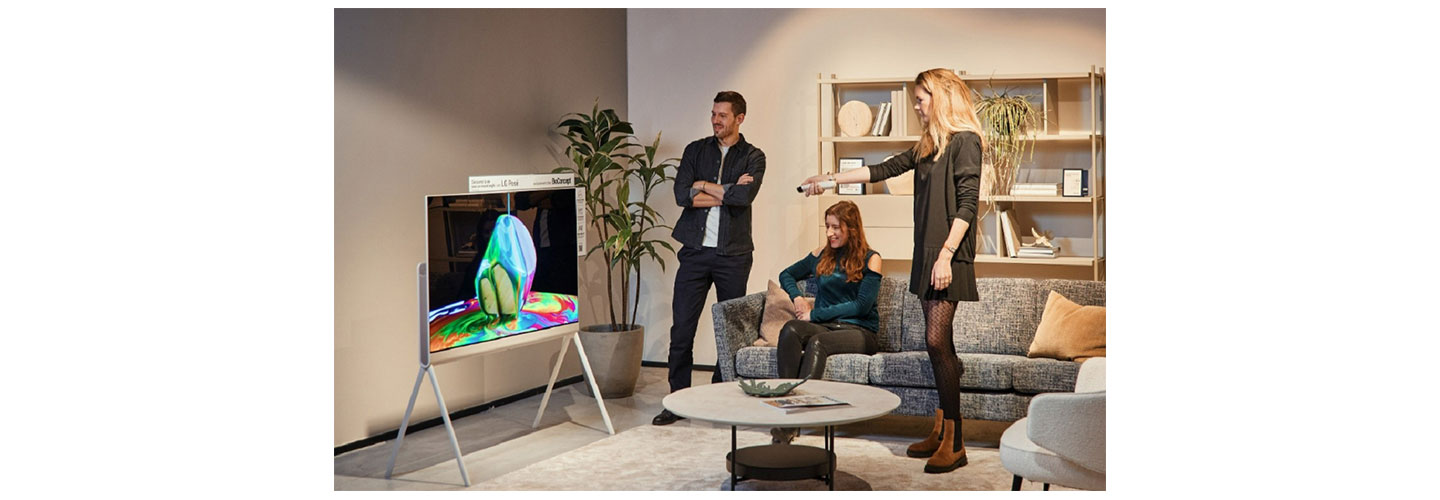 A photo of three people in a living room enjoying the LG Objet Collection Pose