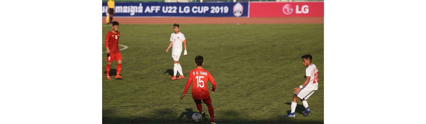 A pitch-side advertisement board displays LG logo in the distance while some soccer players vie for the ball on the ground.