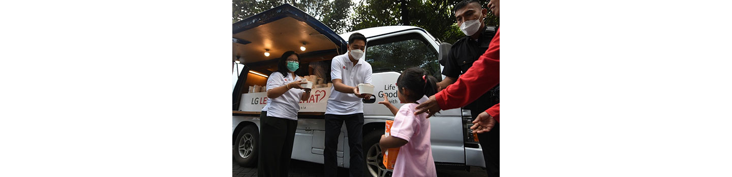 LG Indonesia staff handing over prepared food to a young girl during LG Lebaran Sehat event