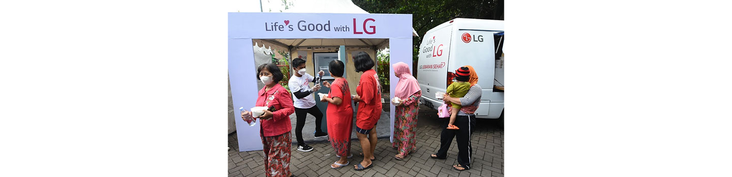 LG Indonesia staff handing over a bottle of water to people waiting in line during the annual LG Lebaran Sehat event