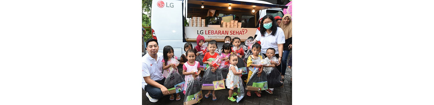 LG Indonesia staff posing together with children all holding a bag of goods provided by LG during LG Lebaran Sehat event