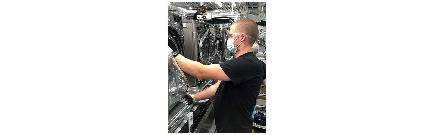 Another factory worker checking the quality of an LG washing machine's door
