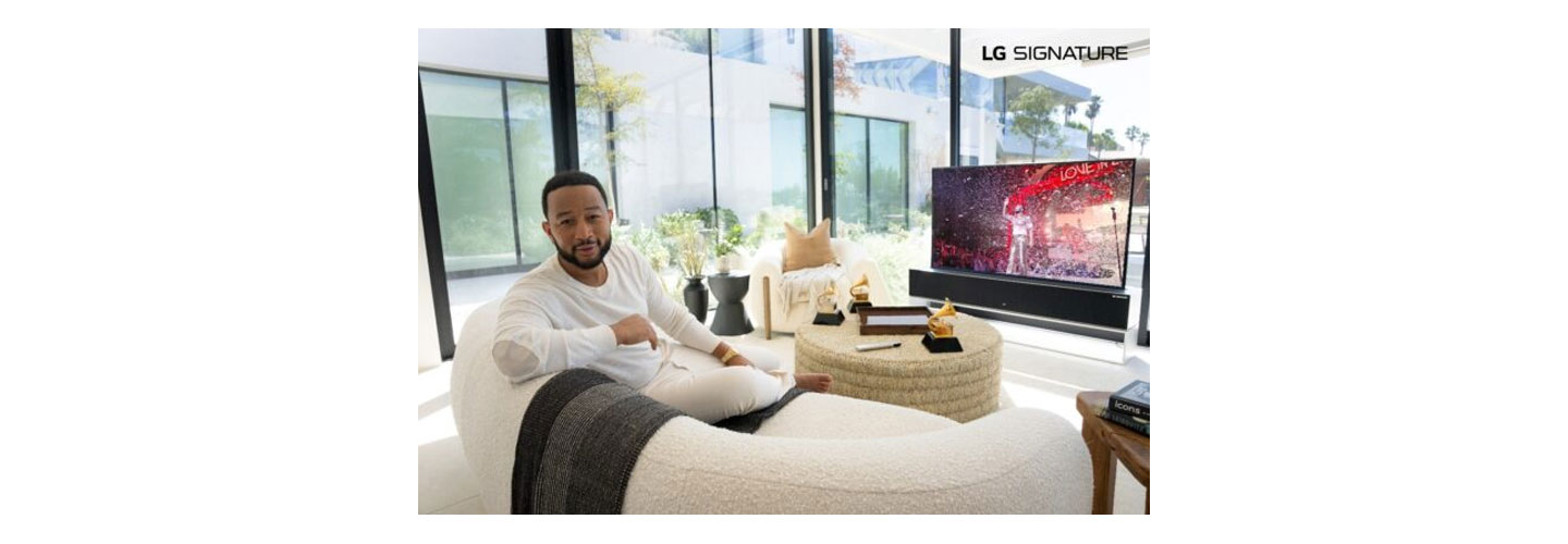 John Legend sitting in front of his LG SIGNATURE OLED R TV while talking to the camera