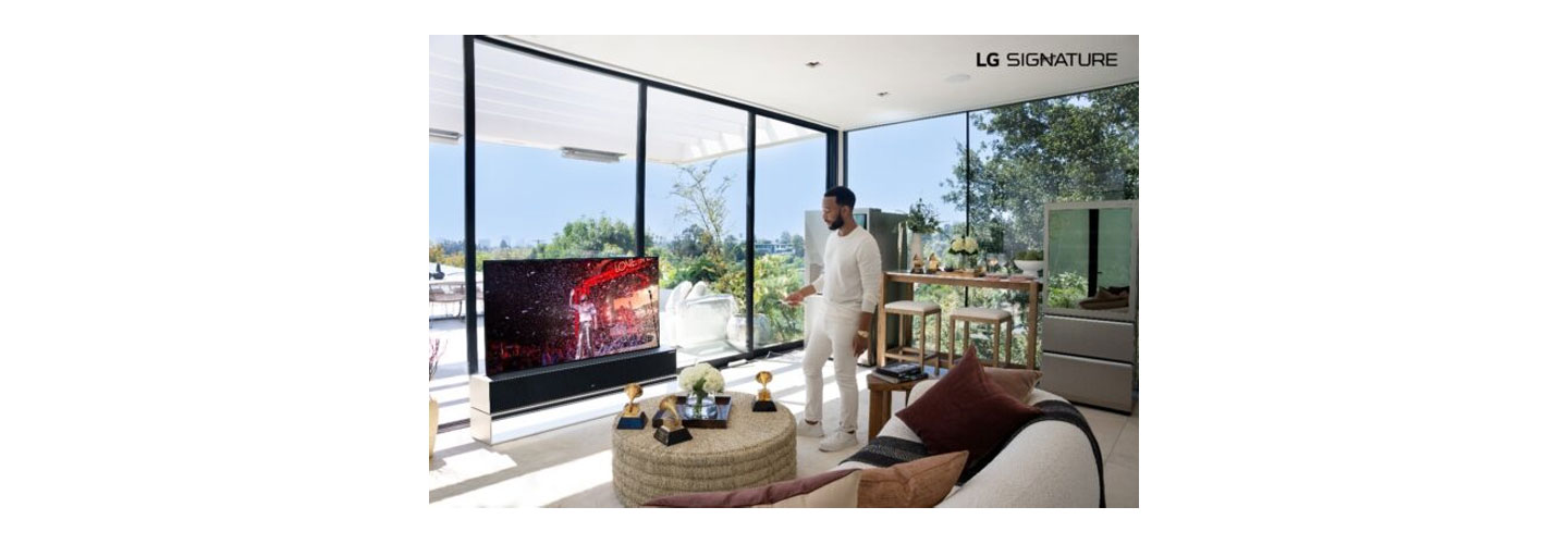John Legend pointing the remote at his LG SIGNATURE OLED R TV