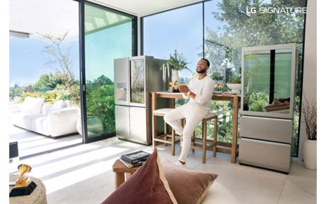 John Legend sitting on a stool between the LG SIGNATURE InstaView Door-in-Door refrigerator and LG SIGNATURE Wine Cellar