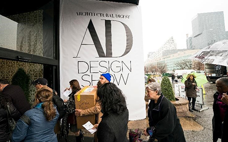 A group of visitors pass by a big logo banner for the 2019 Architectural Digest Design Show in New York City.