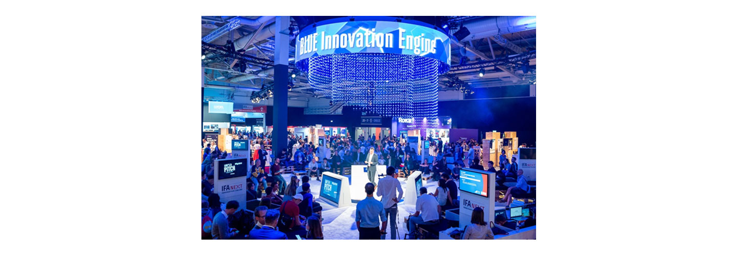 The photo taken during IFA 2022 where many visitors are gathered to listen to the speaker  and the phrase 