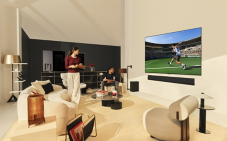 A picture of a woman and a man in a living room watching sports on the OLED TV