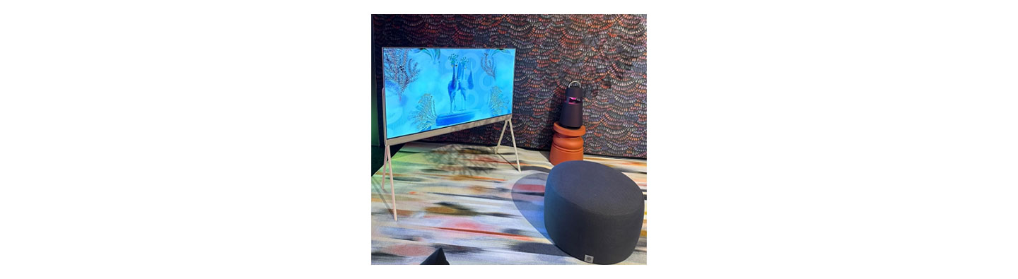 LG OLED Objet Collection Pose standing in the corner of a colorful room at CES 2023 next to the LG XBOOM speaker in black